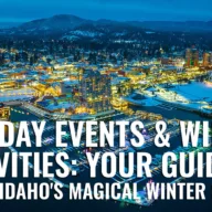 Aerial view of downtown Coeur d'Alene Idaho illuminated at winter dusk with snow-covered cityscape, waterfront resort district, and mountain backdrop