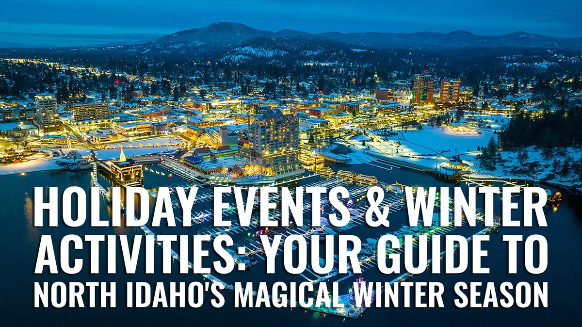 Aerial view of downtown Coeur d'Alene Idaho illuminated at winter dusk with snow-covered cityscape, waterfront resort district, and mountain backdrop