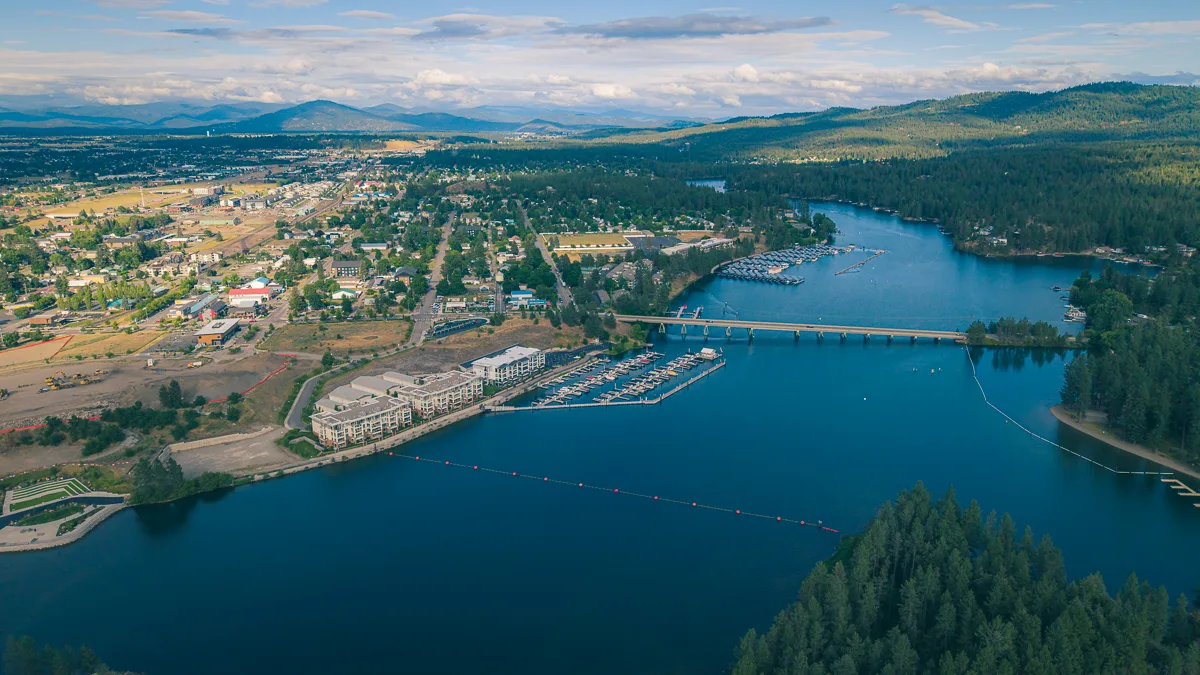 Aerial view of Post Falls, Idaho, along the Spokane River with a marina, waterfront homes and surrounding hills.
