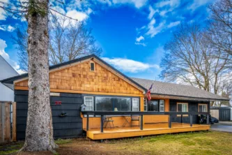 Front exterior of remodeled home at 1215 N 1st Street, Coeur d’Alene ID — single-level four-bedroom home near downtown with wood siding, large front deck, and C-17 zoning.